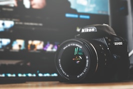 black and white Nikon D3400 DSLR camera on brown surface
