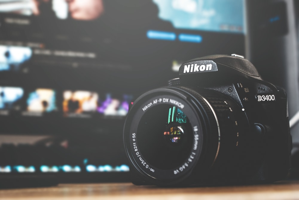 black and white Nikon D3400 DSLR camera on brown surface