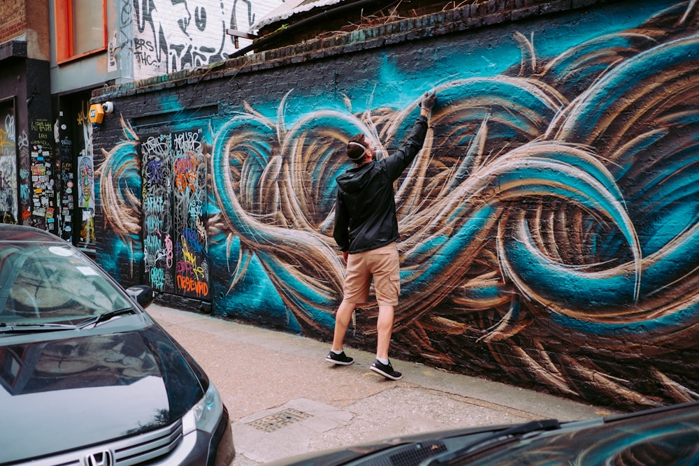 man painting on wall during daytime