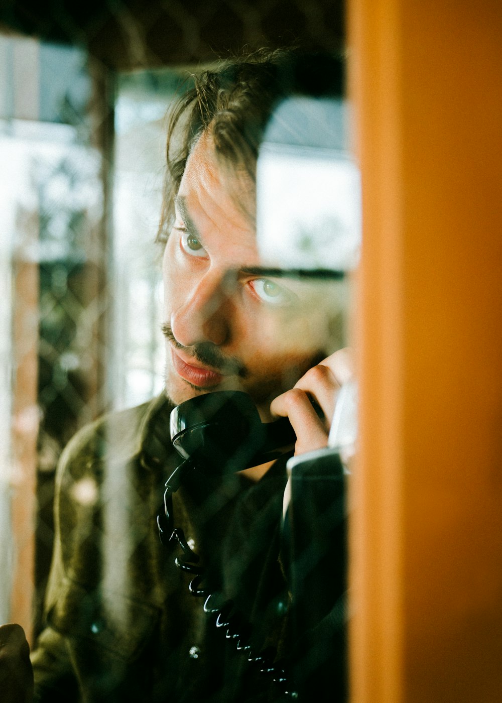 man holding telephone in telephone booth