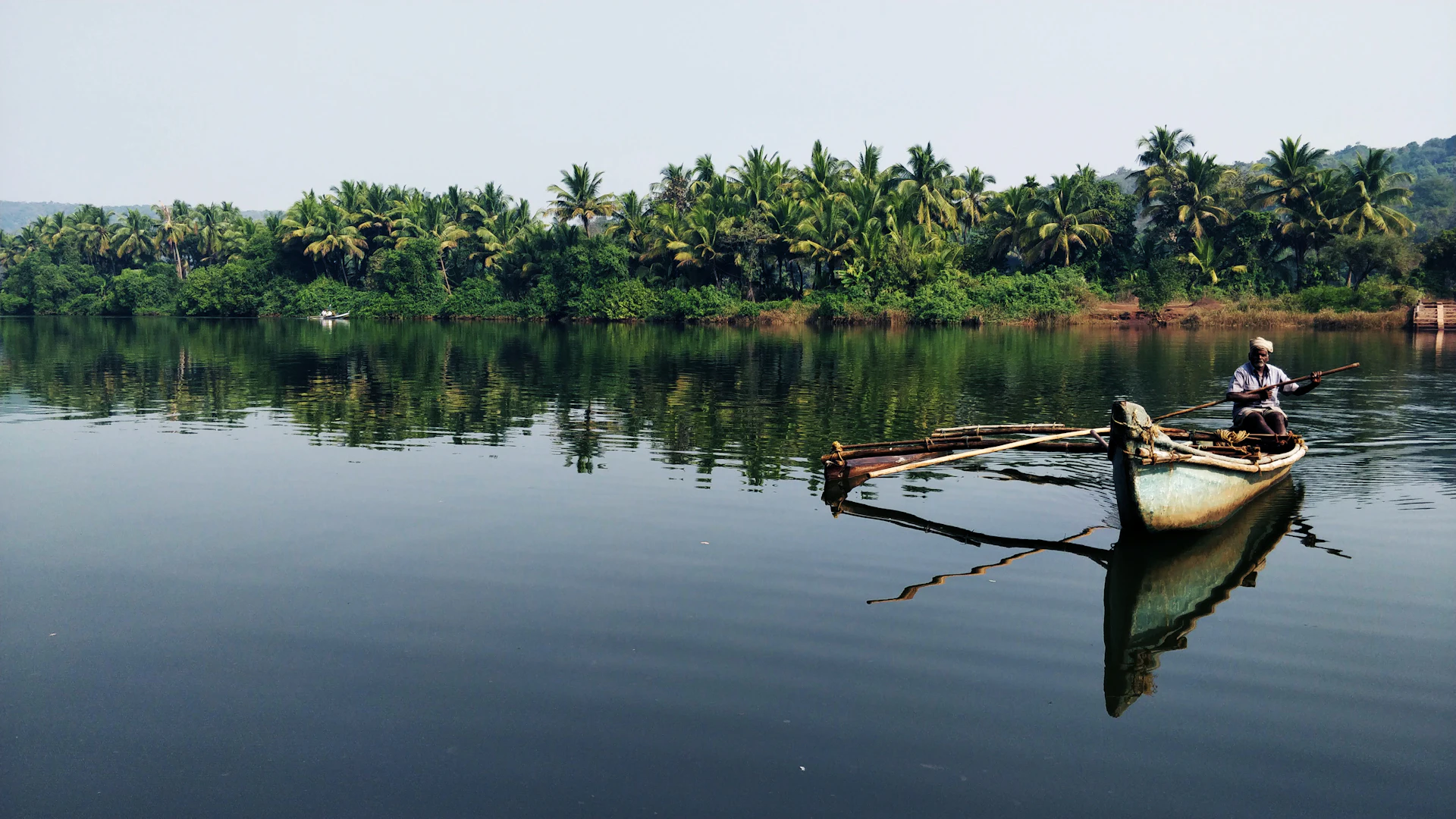 Man sitting on a wooden boat on the Karli backwaters near Tarkarli, Konkan