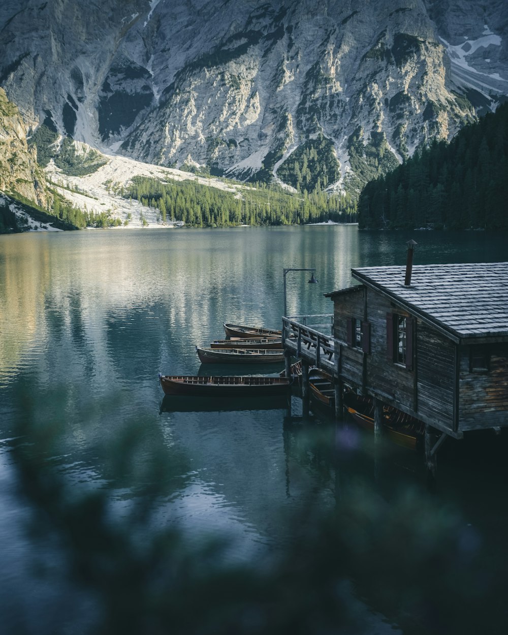 three brown wooden boats parked beside wooden house on lake