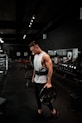 man in white tank top holding bumper plate