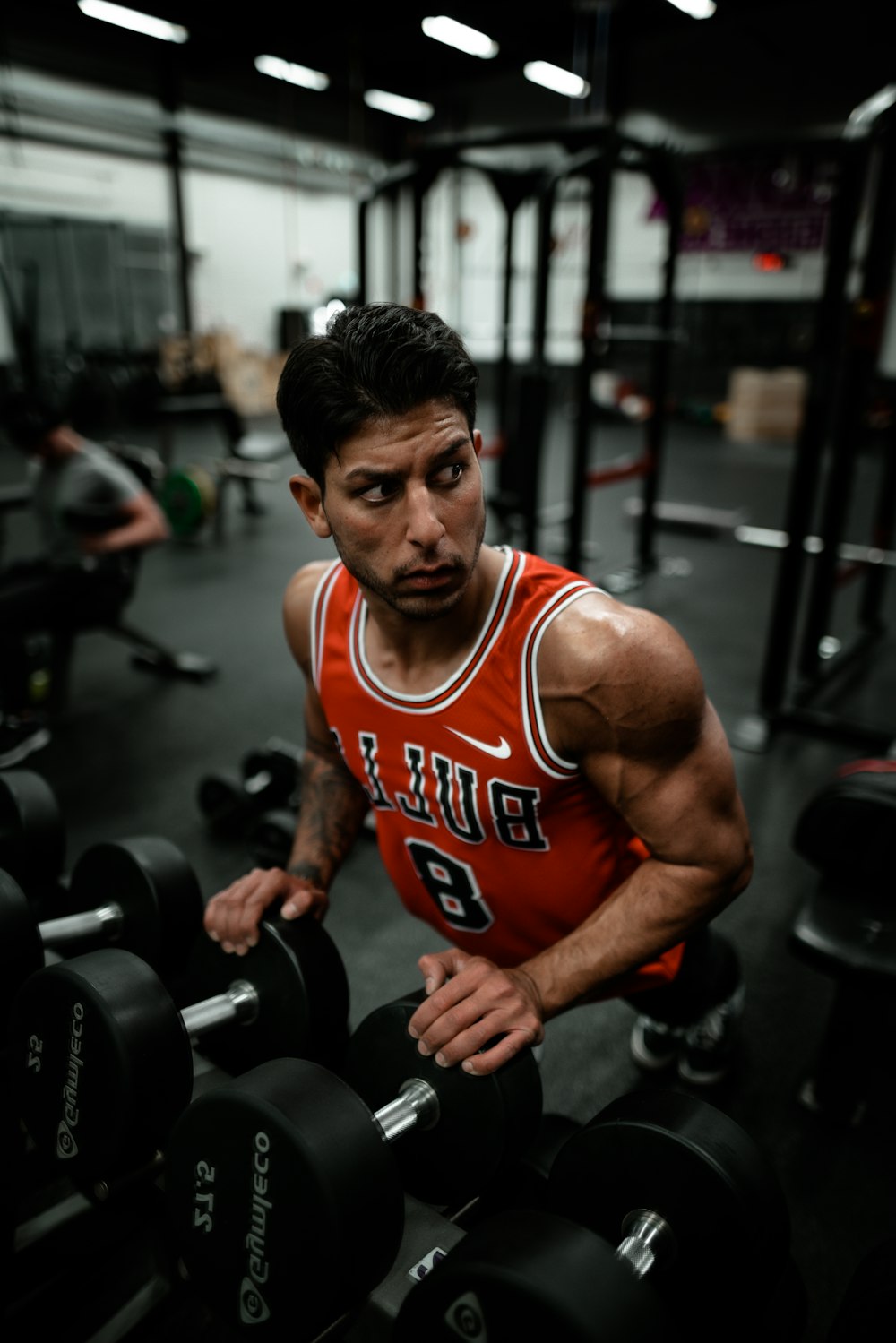man in red Chicago Bulls jersey doing push-up exercise on dumbbells