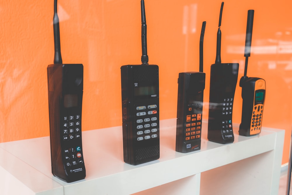 five assorted-brand wireless phones on desk