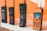 A collection of four vintage mobile phones displayed in a row against an orange background. The phones vary in size and shape, showcasing different designs from past eras, including prominent antennas and tactile keypads.