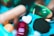 A collection of various pills and capsules, including a prominent green gel capsule and a heart-shaped white tablet. The image has a colorful and slightly abstract presentation with a blurred, artistic style.