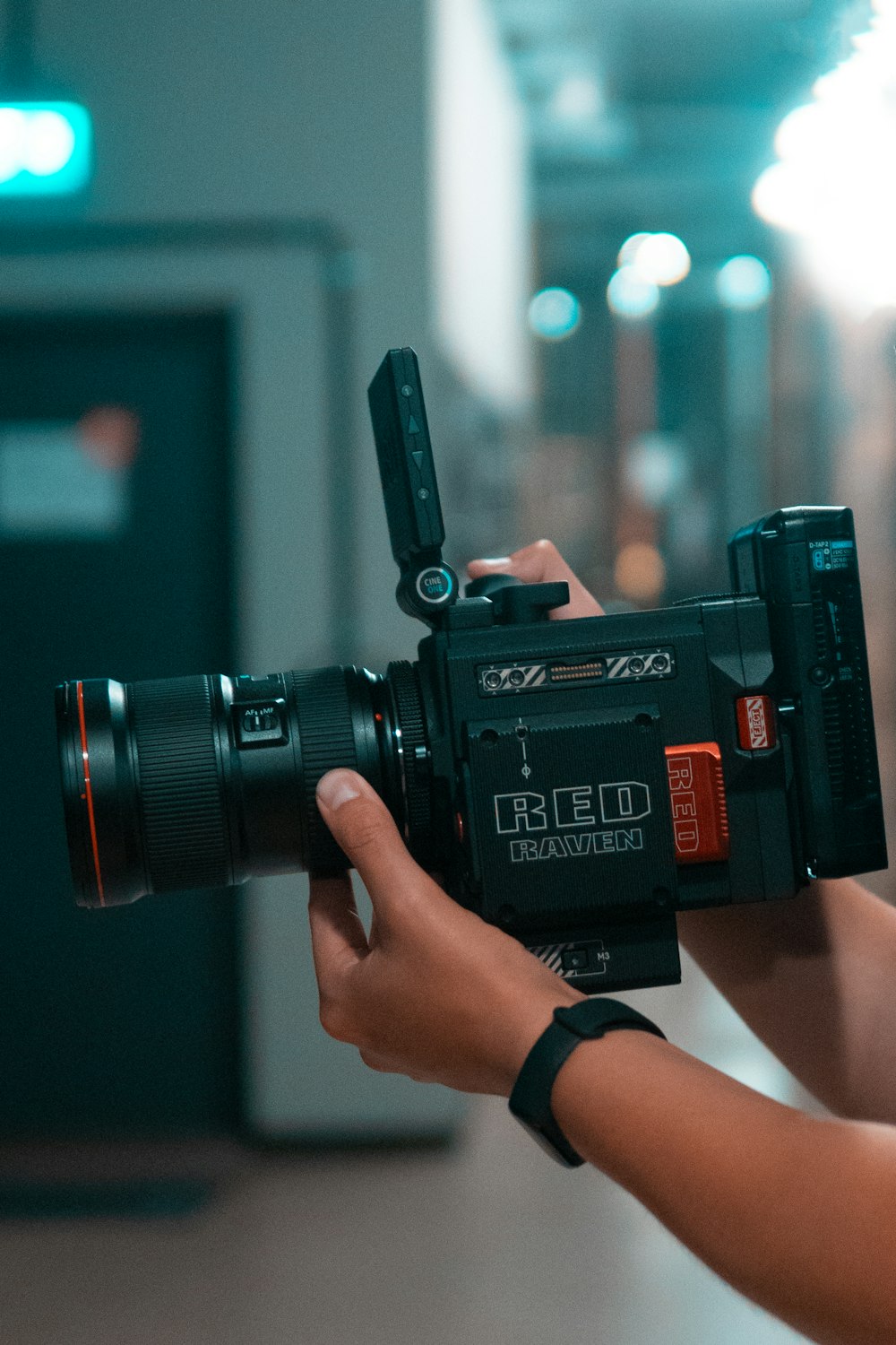 person holding black video camera in the hallway