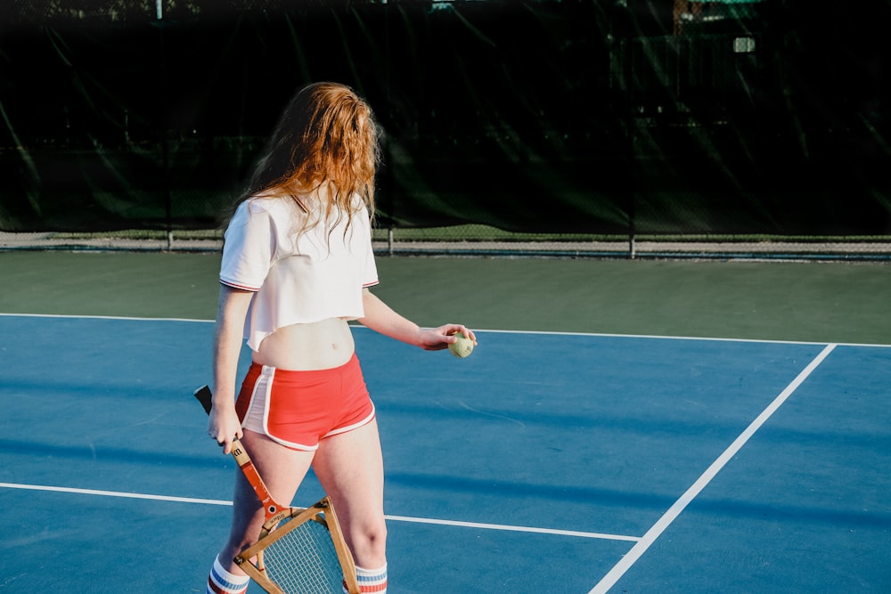 woman in white crop top and red and white dolphin shorts holding green ball and rocket