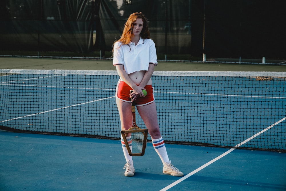 Stehende Frau mit Tennisball und Schläger auf dem Tennisfeld
