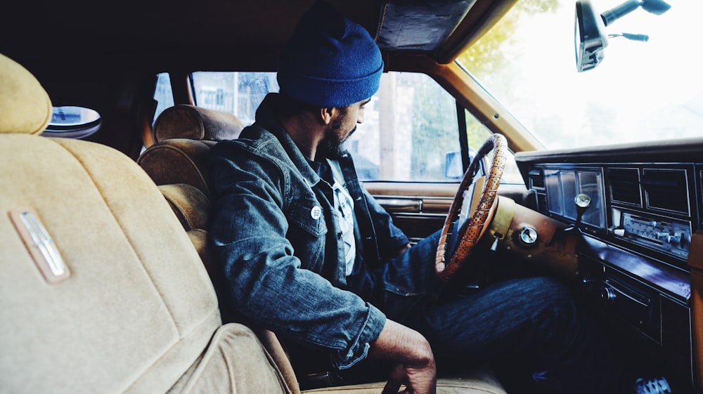 man wearing blue denim jacket sitting inside vehicle