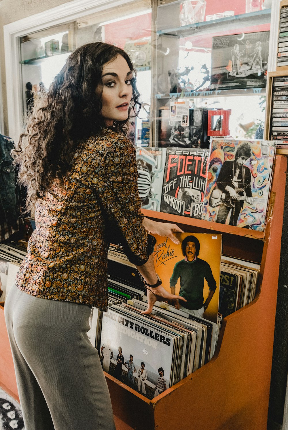 woman standing and looking side view while touching album sleeve inside store