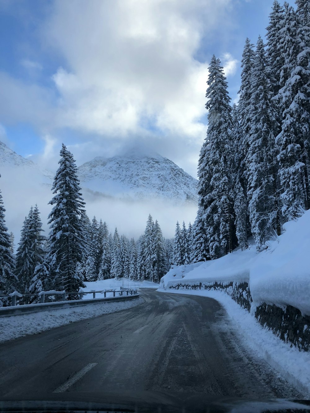 estrada de asfalto ao lado de árvores nevadas e montanha