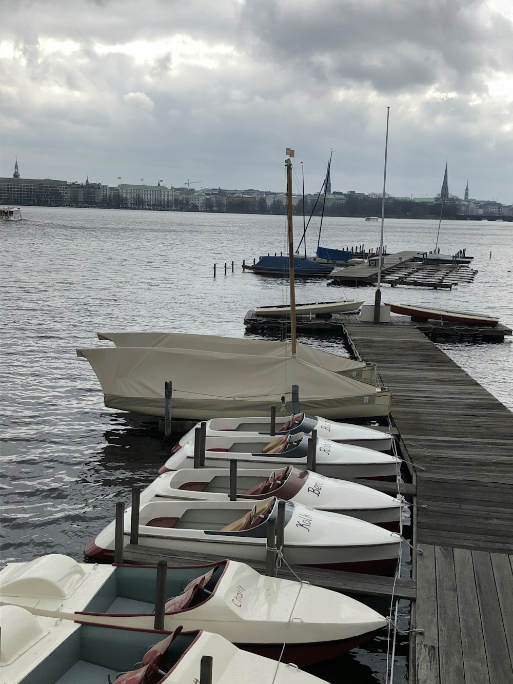 boats on wooden dock under gray sky during daytime