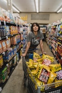 woman in gray shirt holding shopping cart with Original Potato Chips bag lot