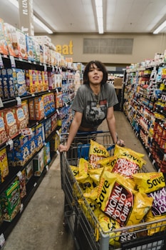 woman in gray shirt holding shopping cart with Original Potato Chips bag lot