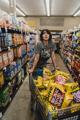 woman in gray shirt holding shopping cart with Original Potato Chips bag lot