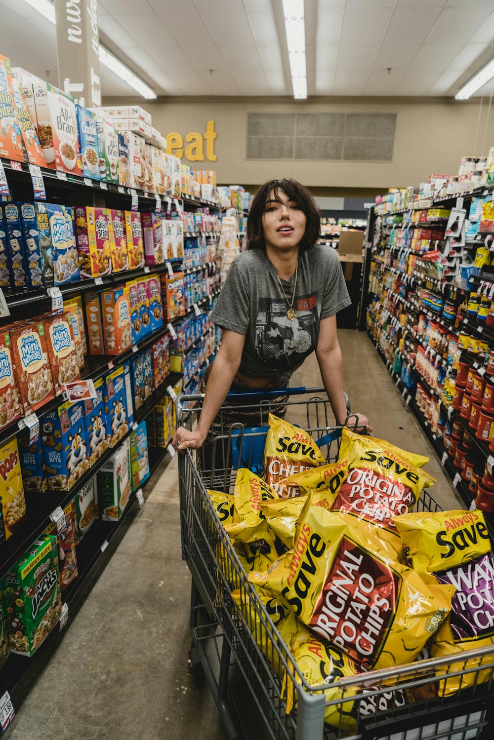 woman in gray shirt holding shopping cart with Original Potato Chips bag lot
