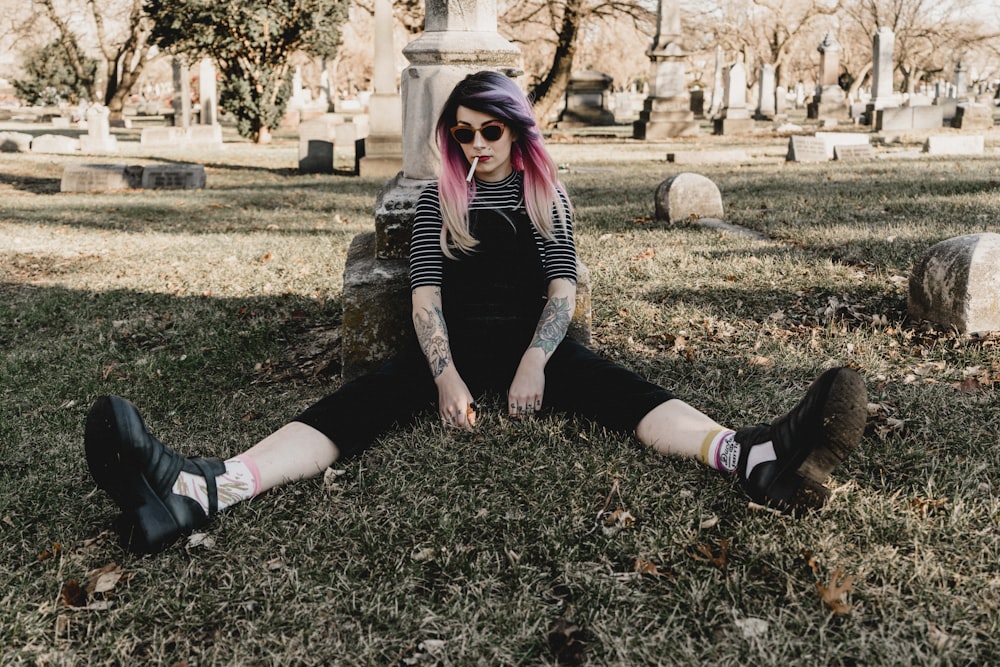 woman sitting on grass with legs separated surrounded with trees