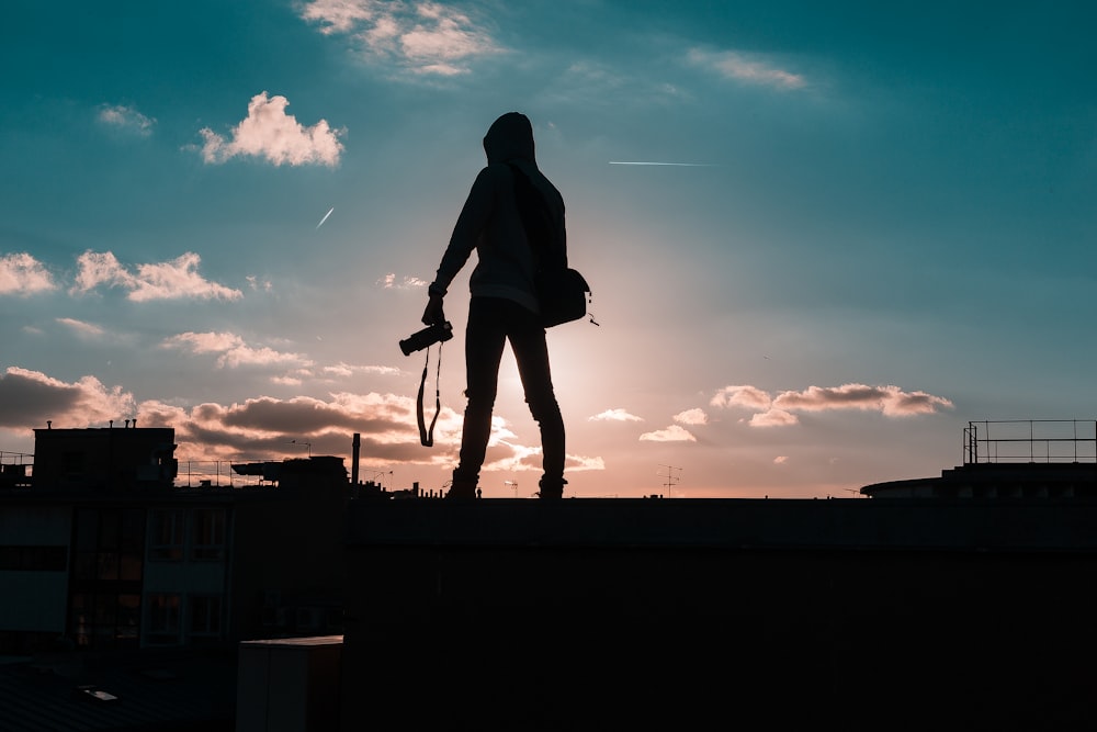 silhouette of person standing and holding DSLR camera