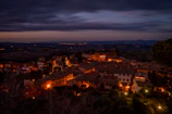 Evening view of a quaint village street lit by warm lanterns.