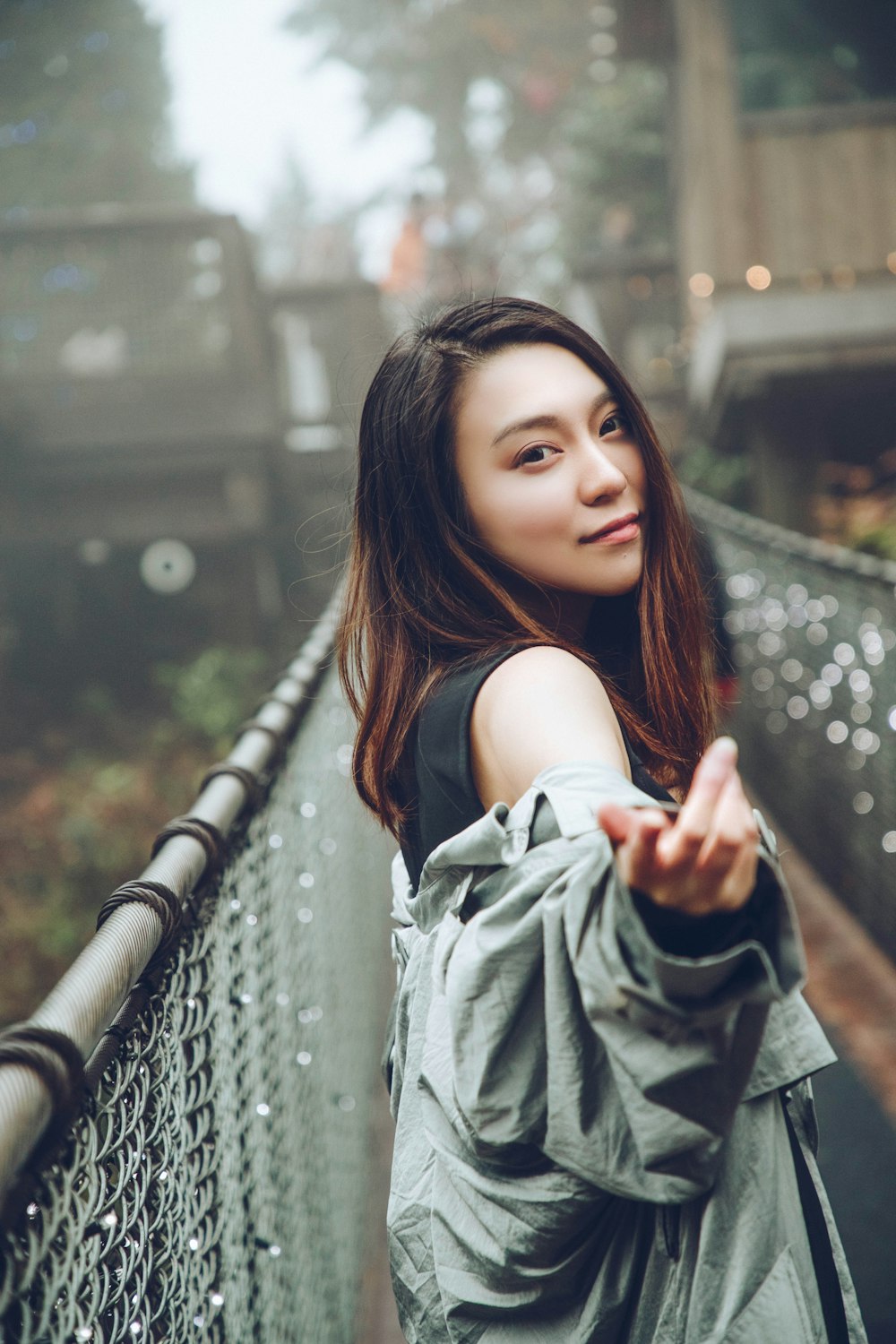 woman in gray coat on bridge on selective focus photography