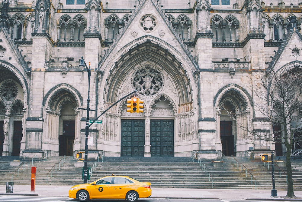 yellow sedan parking near road and building