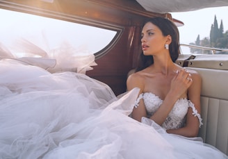 woman wearing white sweetheart-neckline wedding dress inside vehicle