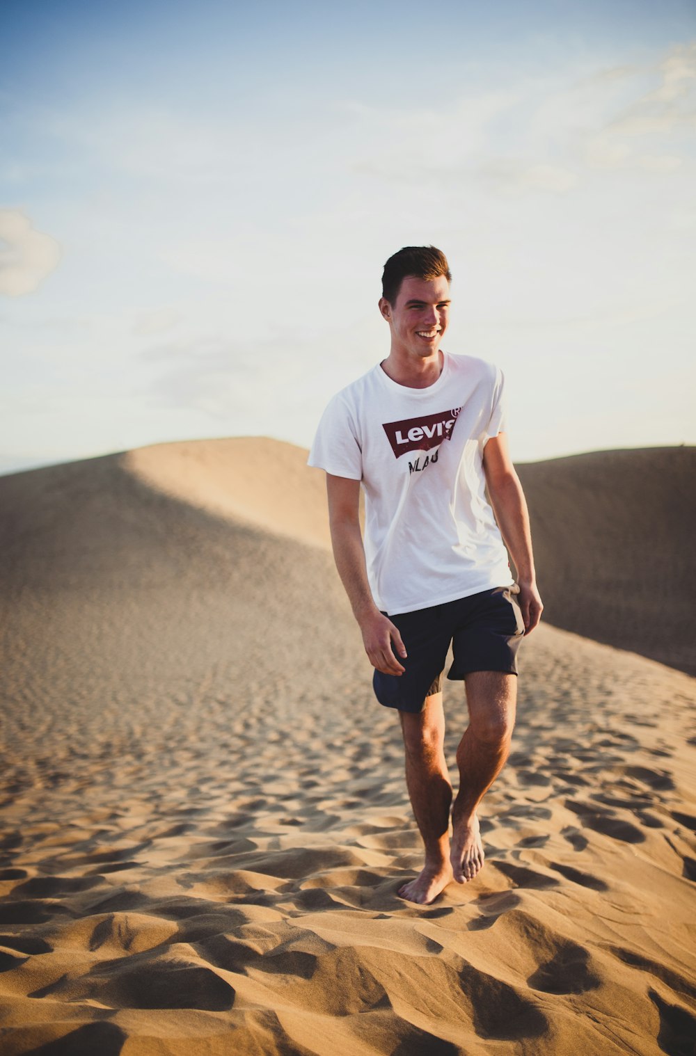 hombre en camisa blanca de Levi's caminando en el área del desierto