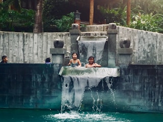 Family enjoying a spacious pool with integrated seating and waterfall feature.