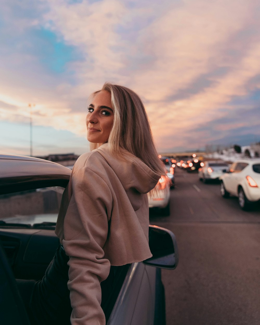 woman wearing beige pullover hoodie inside car during daytime