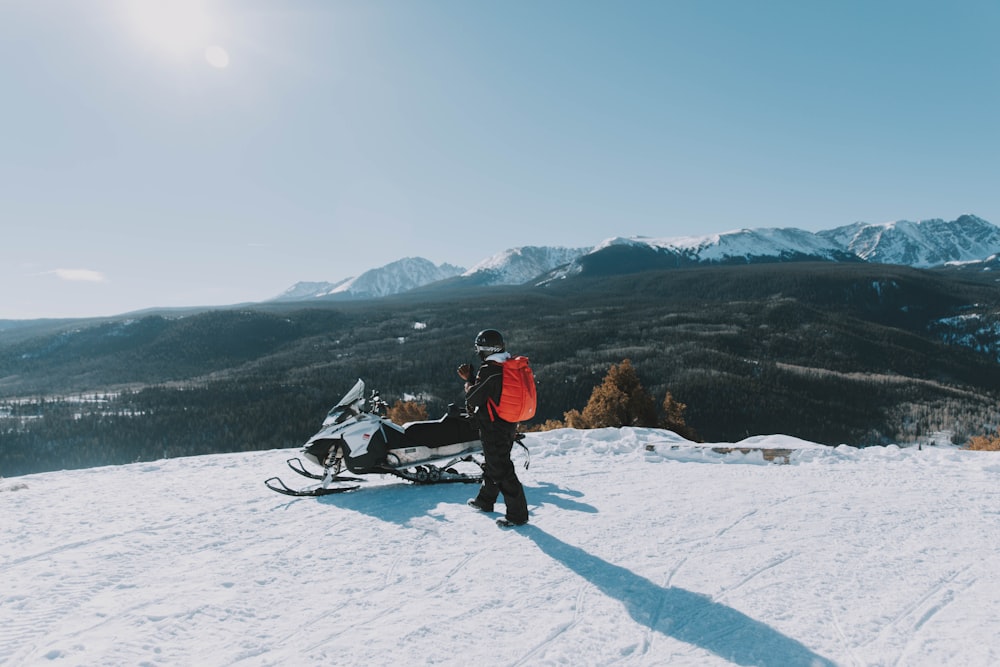 man walking near the white and black snowmobile