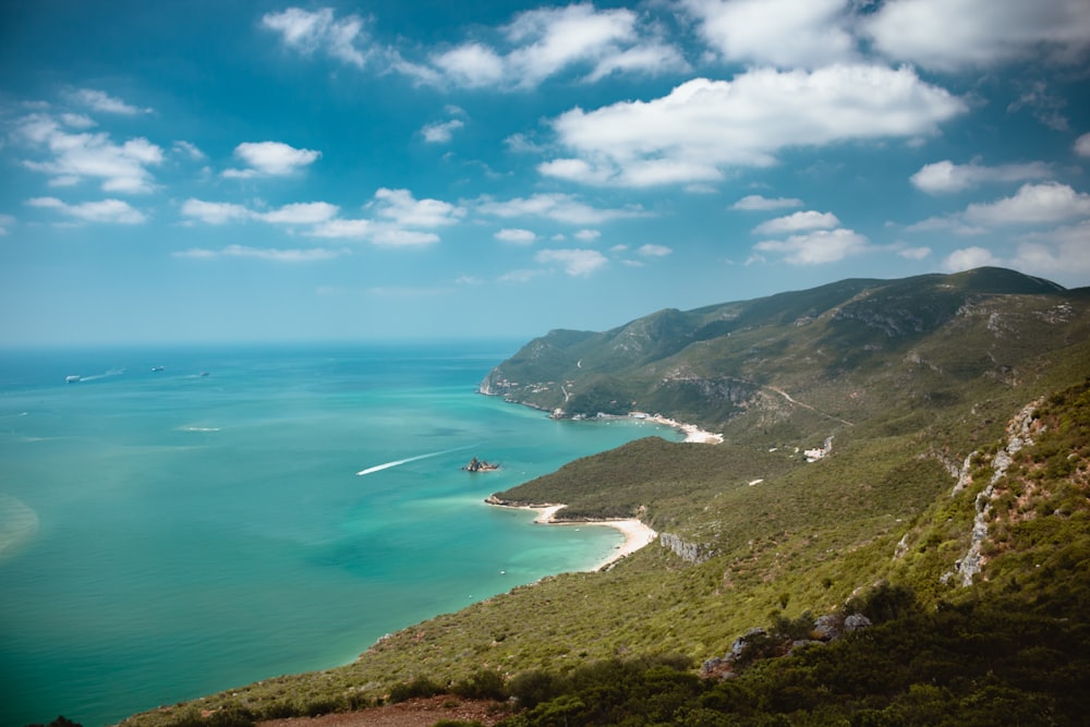 body of water beside mountain during daytime