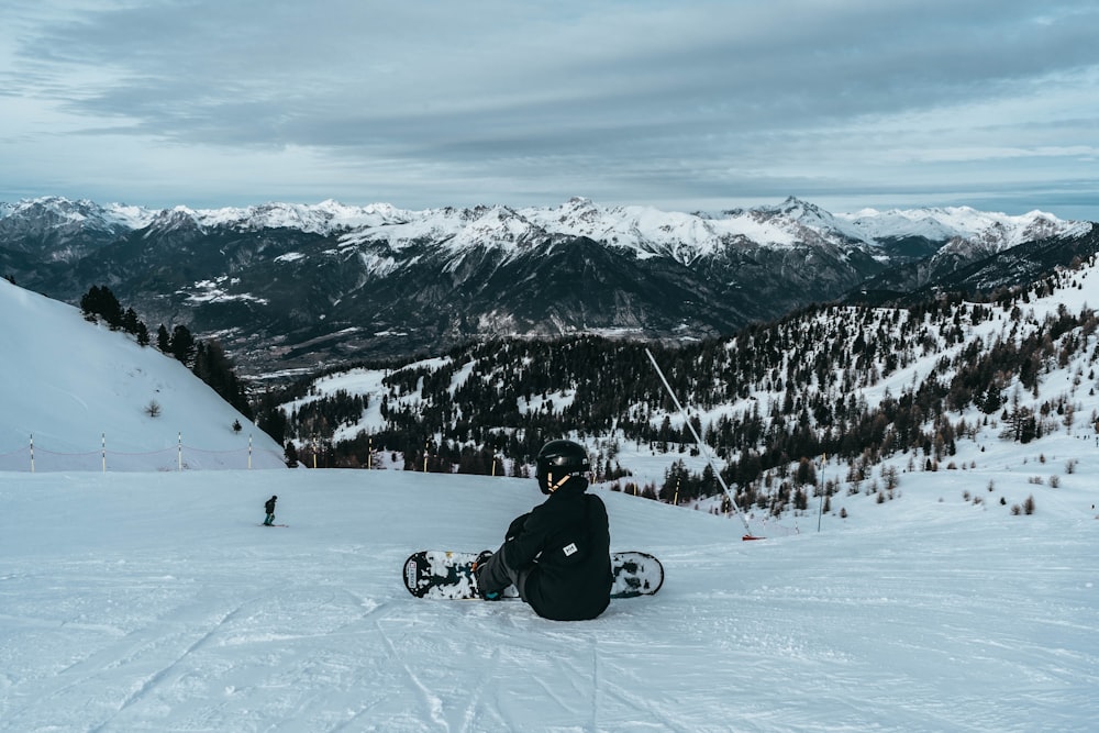 person sitting on snow under clear blue sky during daytime