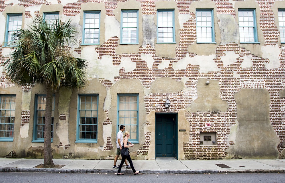 man and woman walking on pathway near building