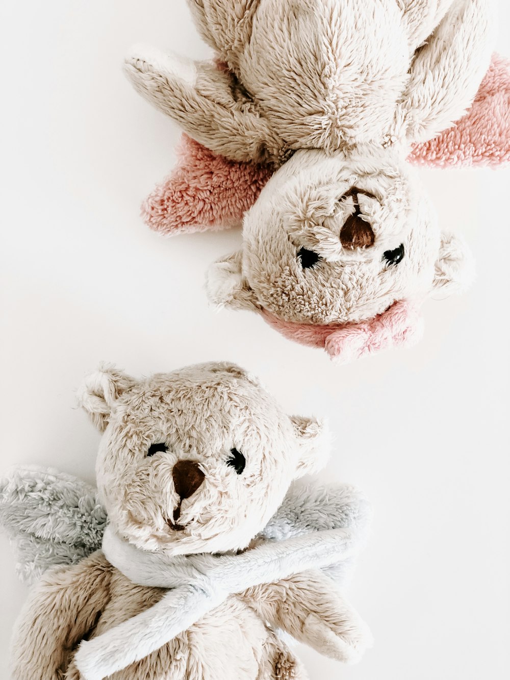 two brown bear plush toys on white surface