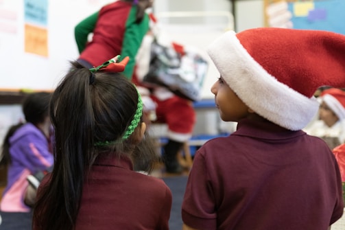 A candid shot of children laughing together with Santa in the background.
