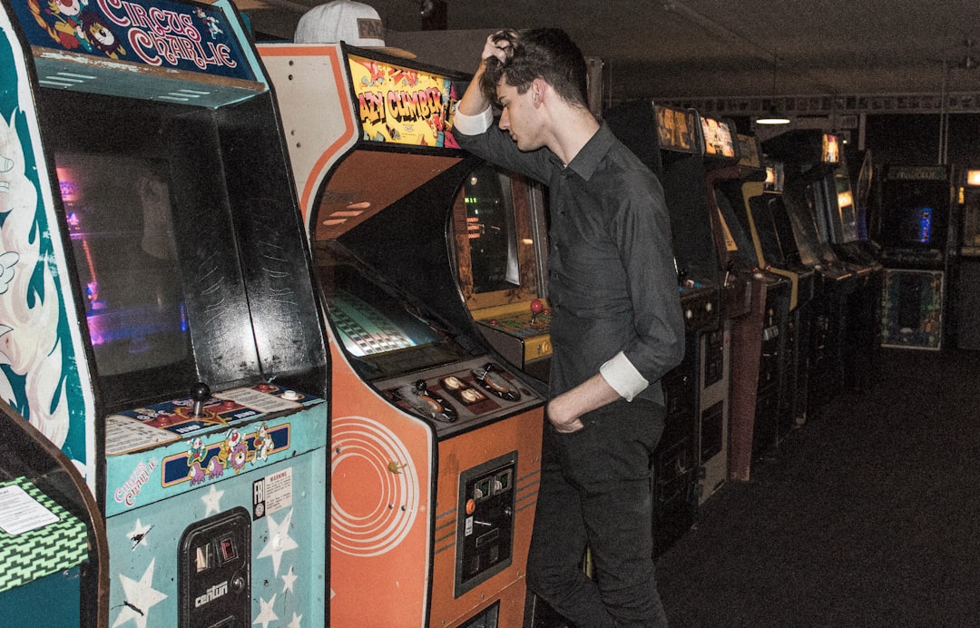 man standing in front of arcade machine,