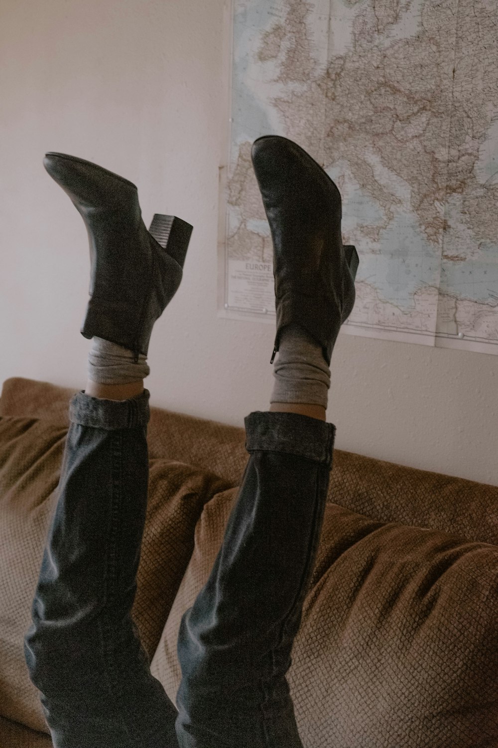 person wearing pair of black leather ankle boots while feet is up in air