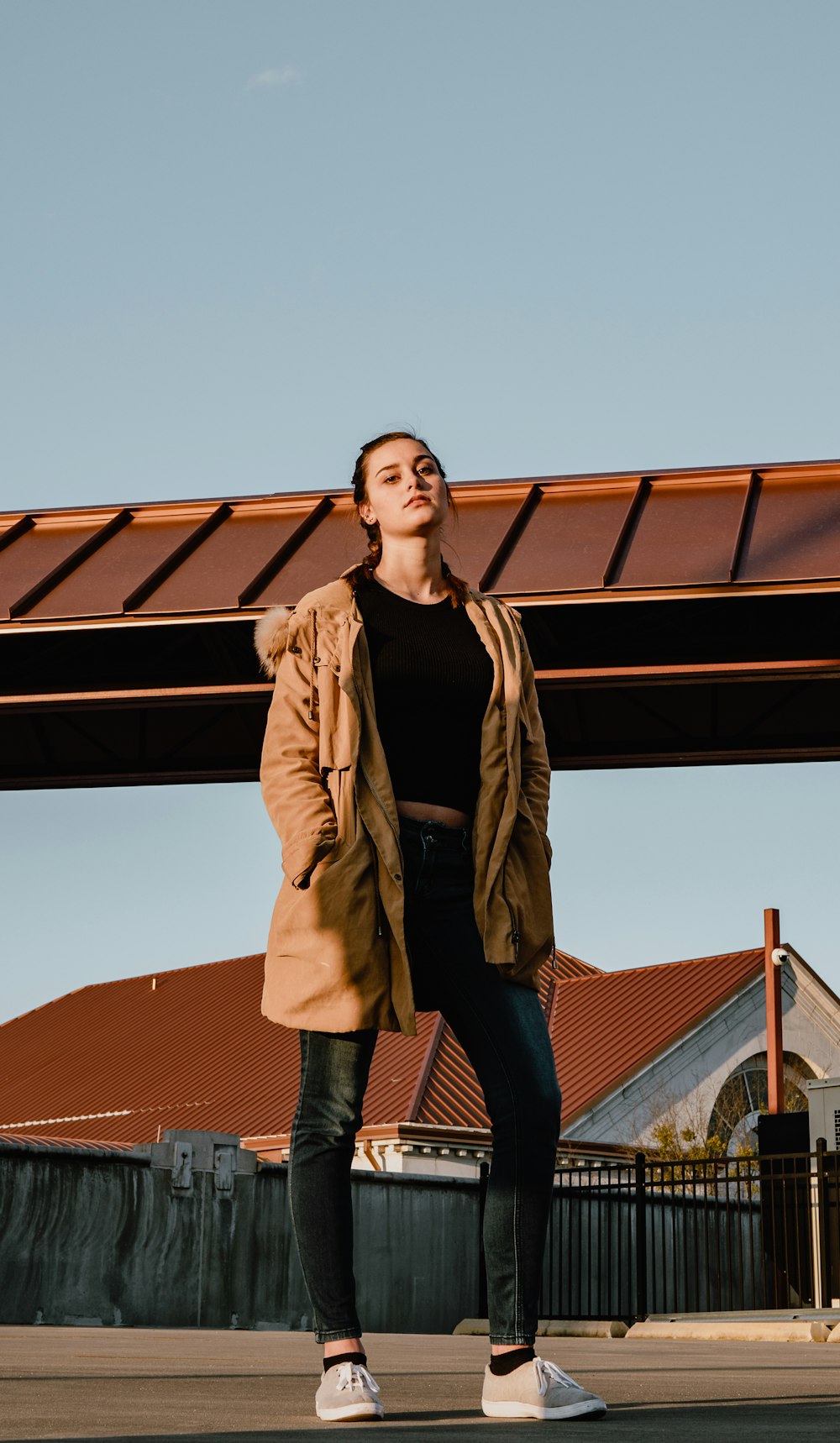 woman in black shirt and brown winter jacket standing on road during daytime