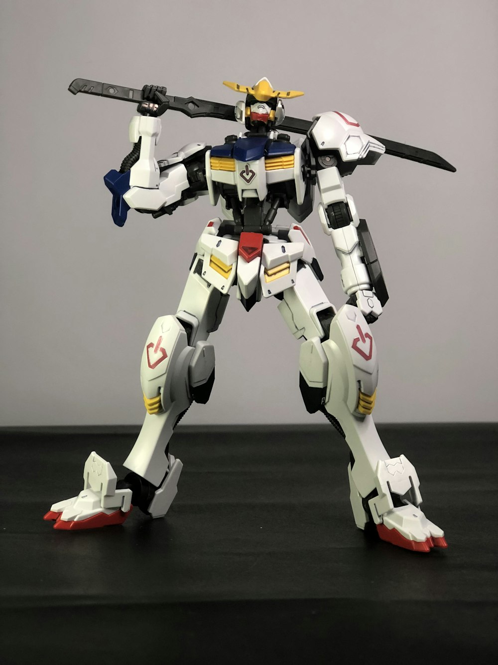 Robot bianco, blu e giallo che tiene la spada giocattolo su pannello nero