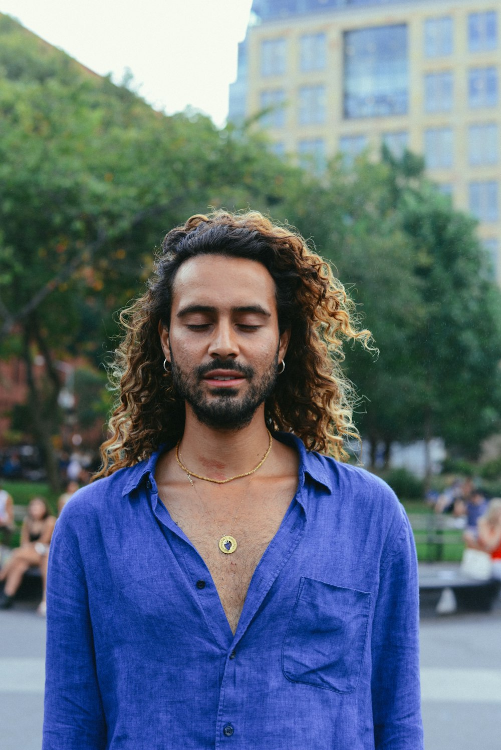 man closing his eyes while standing on park