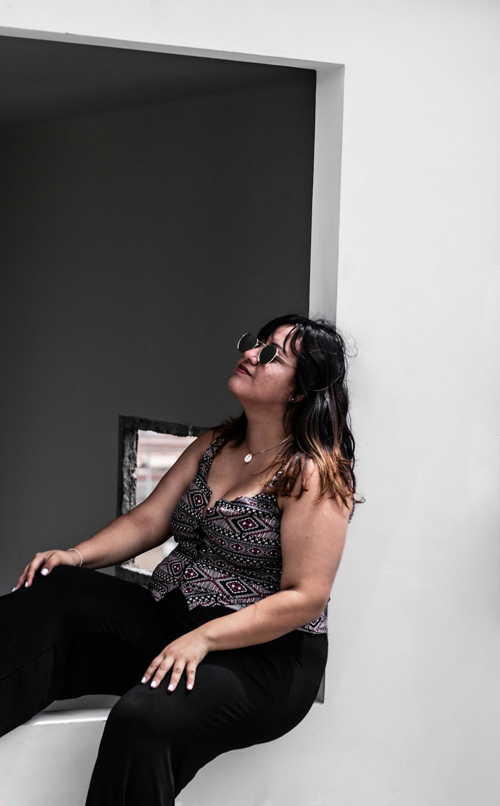 woman in black and grey aztec sleeveless top sitting by the window