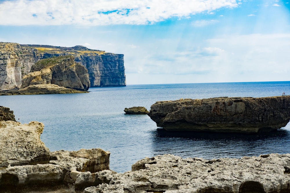 cliff beside sea water under bright sky