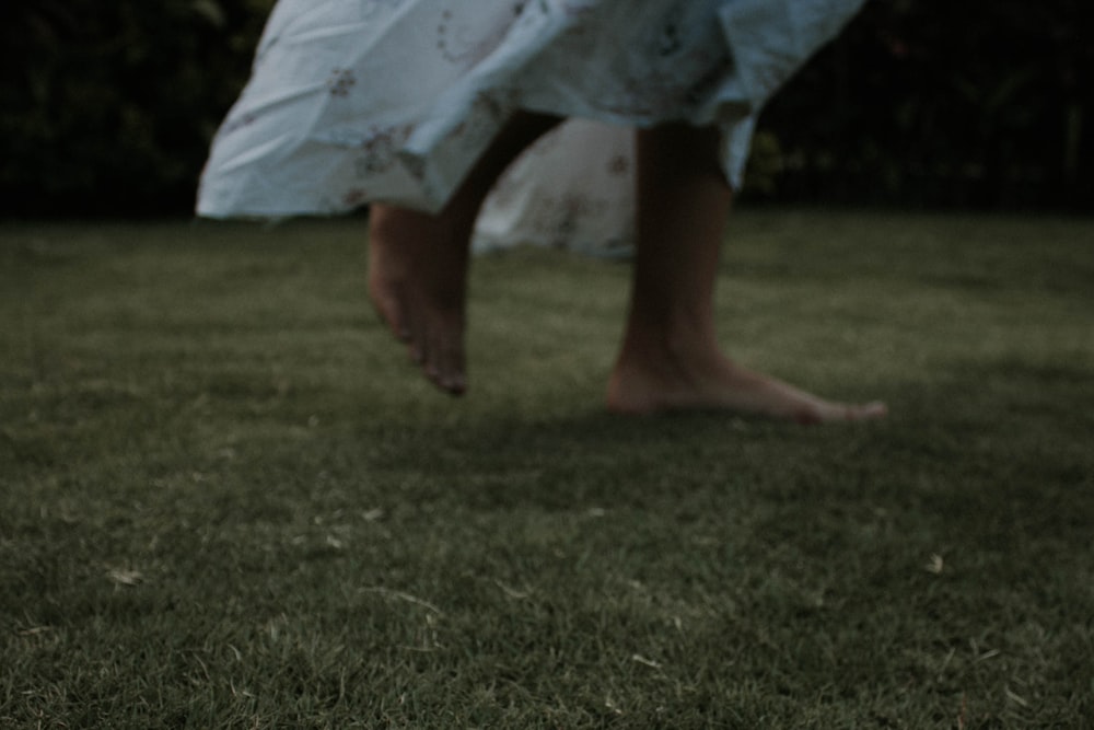 person wearing white dress walk in lawn