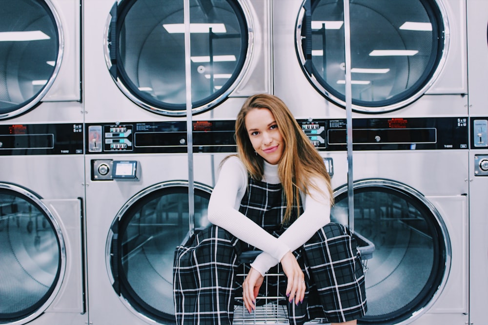 woman sitting on metal in front of laundry machines