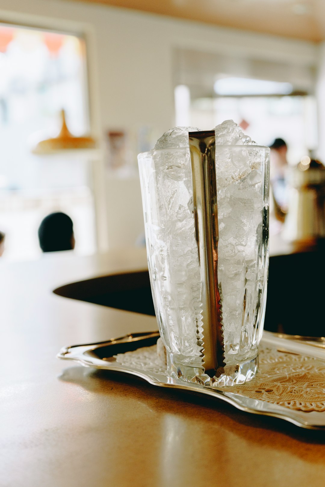  clear drinking glass filled with ice and ice tongs ice box