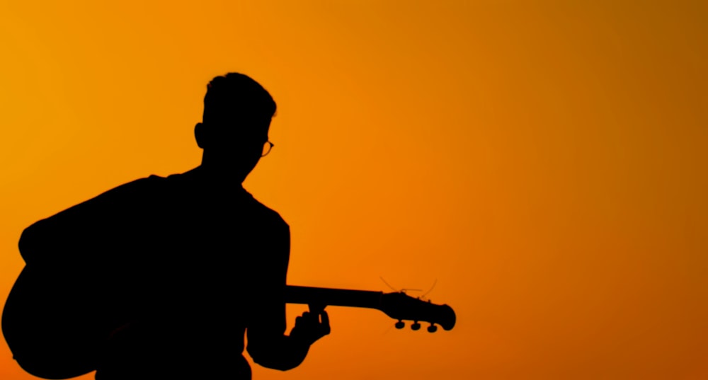 silhouette of person playing guitar