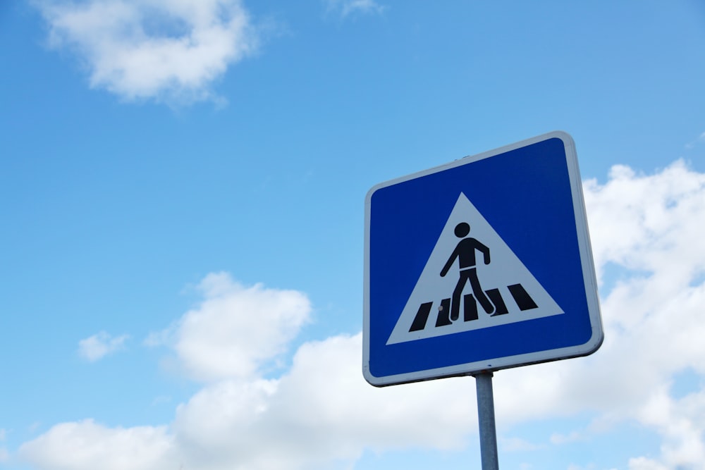 pedestrian signage under blue and white sky