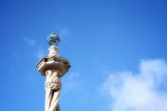 A sturdy pillar standing tall against a clear blue sky, symbolizing strength and stability.